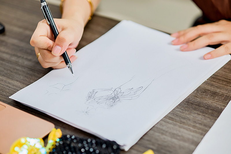 Çalışma masasında Haute couture eskizi, yanında boncuk işleme malzemeleri